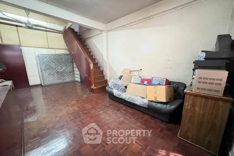 Spacious living room with wooden flooring and staircase, ideal for cozy family gatherings.