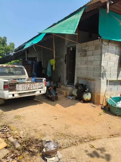 Rustic exterior of a rural home with a pickup truck parked outside, showcasing a simple lifestyle.