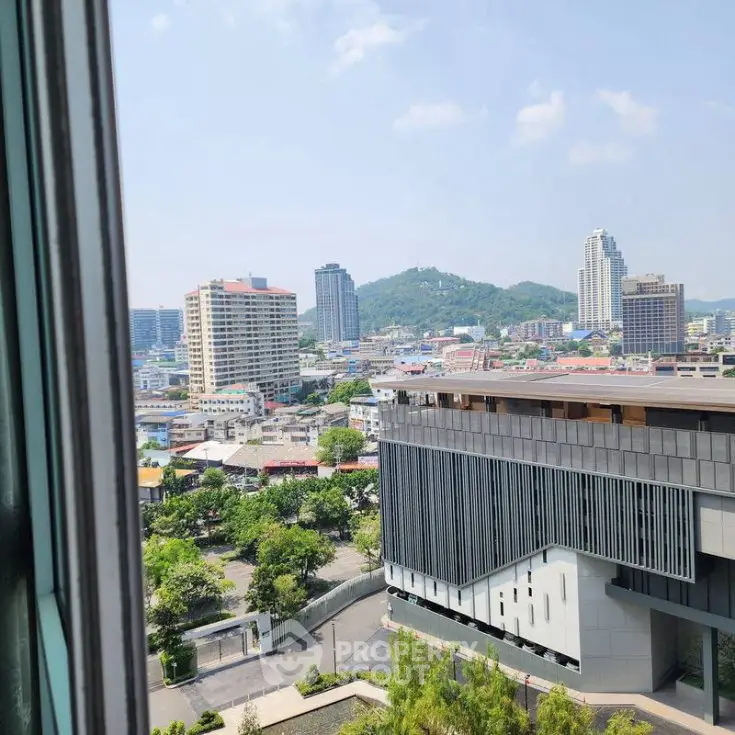 Stunning cityscape view from high-rise building window, showcasing urban skyline and lush greenery.