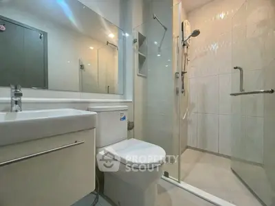 Modern bathroom with glass shower and sleek fixtures in contemporary apartment.