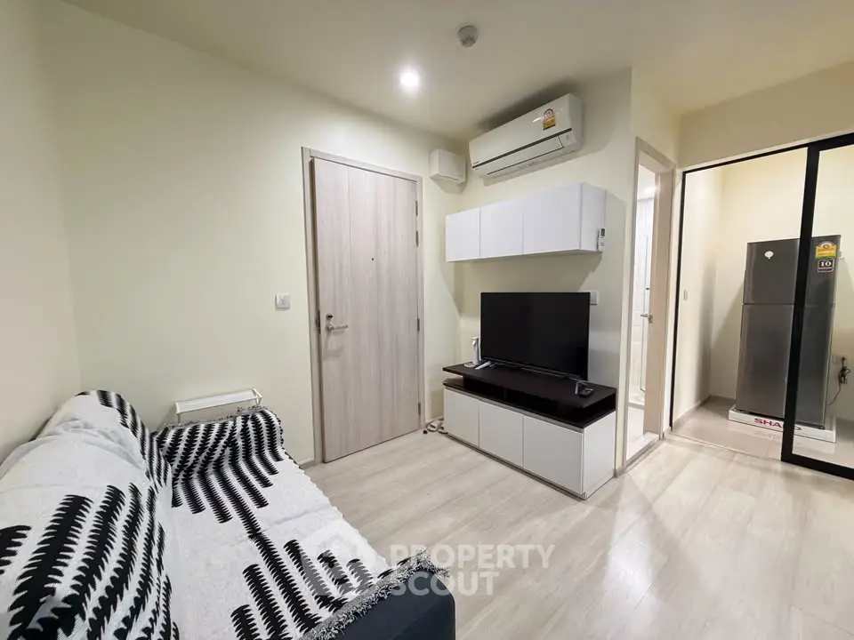 Modern living room with sleek design, featuring a cozy sofa, wall-mounted TV, and air conditioning unit.