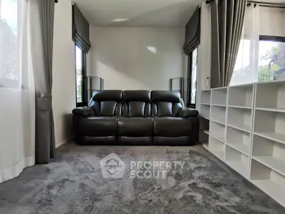 Spacious living room with modern black leather sofa and large windows