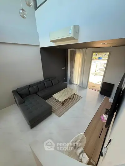 Modern living room with sleek design and large sectional sofa, featuring a balcony view.
