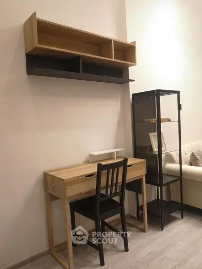 Modern study area with wooden desk, chair, and shelving in a cozy apartment.