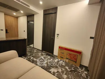 Modern living room with marble flooring and boxed TV, featuring sleek wooden doors and neutral tones.