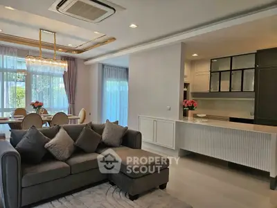 Luxurious open-plan living room with elegant dining area and modern kitchen, featuring plush sofa and stylish lighting.