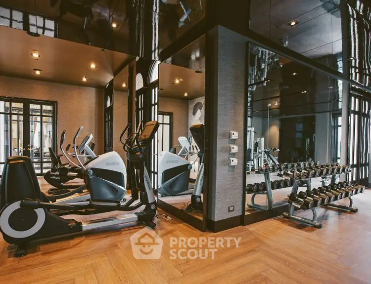 Luxurious gym with modern equipment and elegant wooden flooring in upscale residential building.