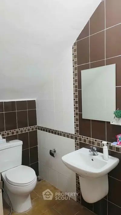 Cozy bathroom with modern fixtures and stylish brown and white tile design.