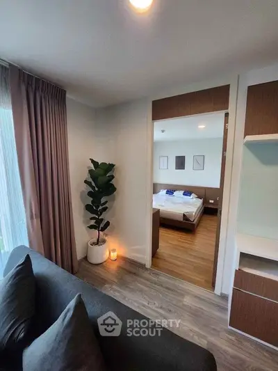 Modern apartment interior with cozy living room and view into stylish bedroom.