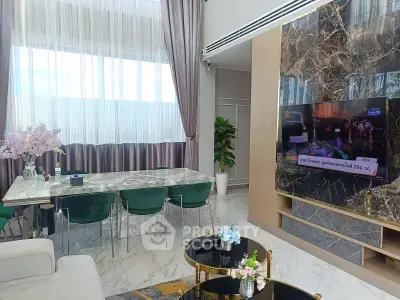 Luxurious living room with marble accents and elegant decor, featuring a large TV and stylish furniture.