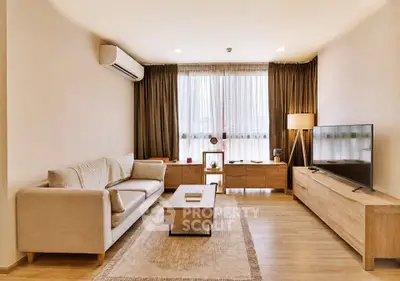 Modern living room with stylish furniture and natural light, featuring a cozy sofa and large TV.
