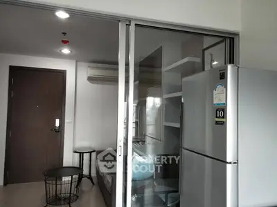 Modern apartment interior with sliding glass doors and stainless steel fridge