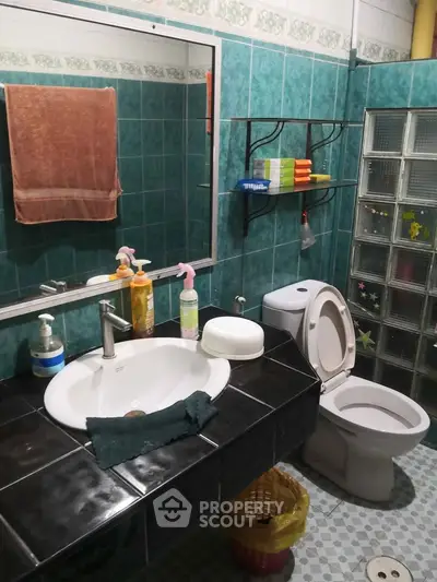 Charming bathroom with teal tiles, modern sink, and organized shelving for a cozy home feel.