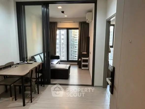 Modern apartment interior with open living and dining area, featuring large windows and sleek furniture.