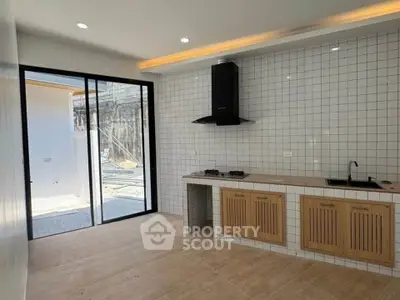Modern kitchen with open layout and sleek design, featuring tiled walls and wooden cabinetry.