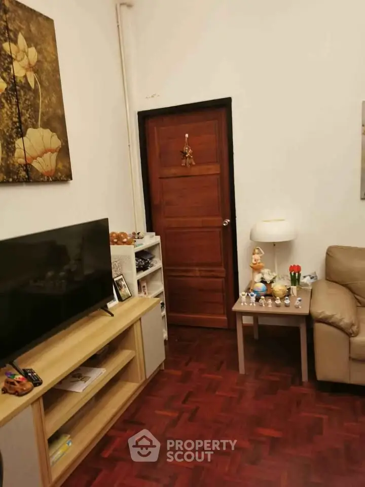 Cozy living room with wooden flooring, modern TV stand, and comfortable seating.