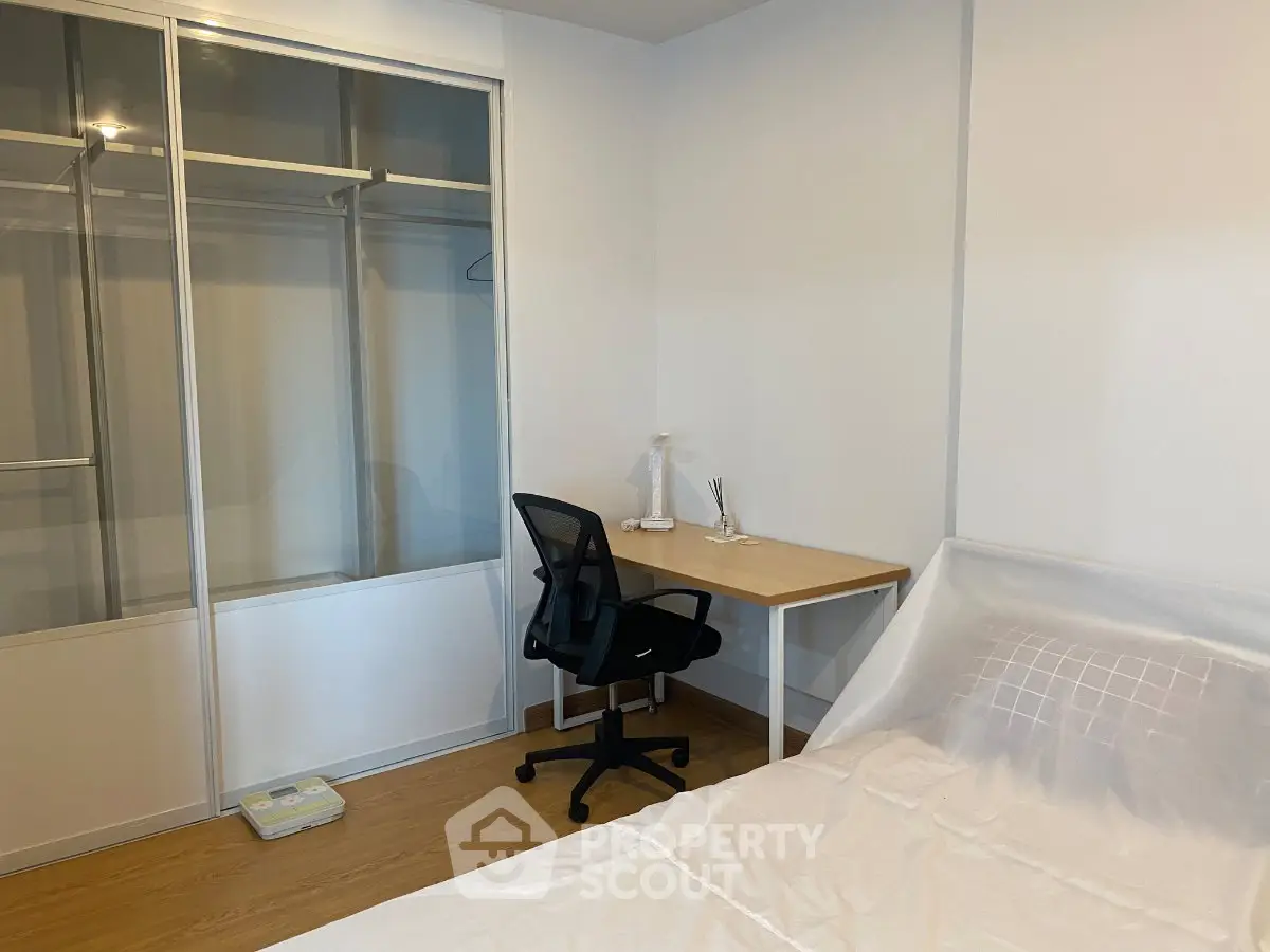 Modern bedroom with study desk and spacious closet in a minimalist apartment.