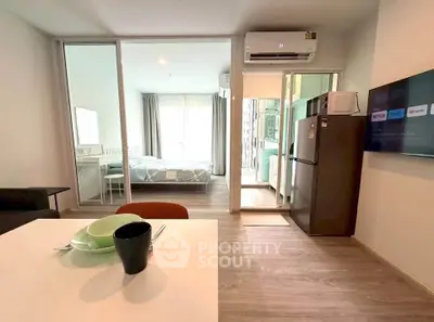 Modern open-plan apartment with sleek kitchen and cozy living area, featuring large windows and stylish decor.