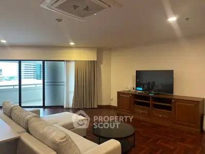 Spacious living room with modern sofa and TV, opening to a large balcony with city views.