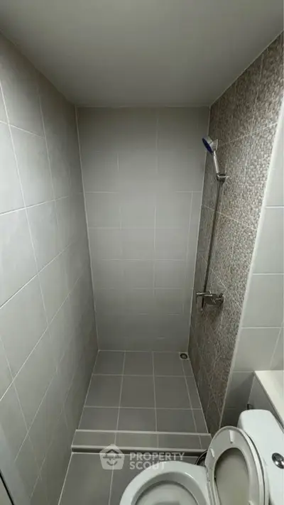 Modern minimalist bathroom with sleek gray tiles and a compact shower area.