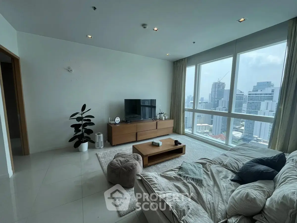 Spacious living room with city view, modern furniture, and large windows in a high-rise apartment.