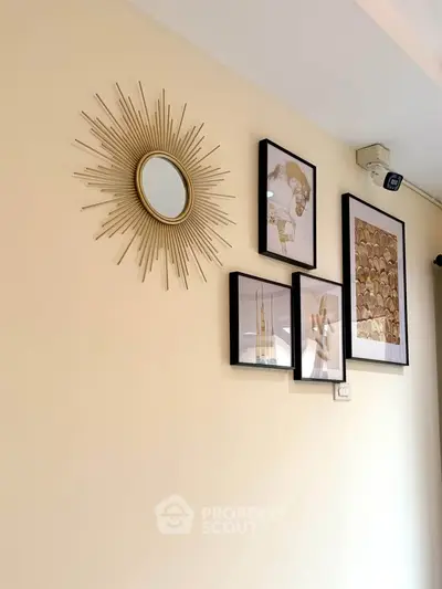 Stylish wall decor with sunburst mirror and framed art in modern living room.
