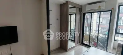 Modern bedroom with large windows and mirrored wardrobe in urban apartment.