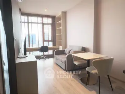 Modern living room with cozy sofa, dining table, and study desk by large window.