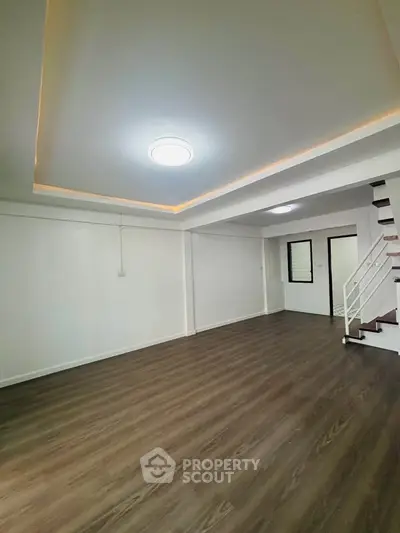 Spacious modern living room with wooden flooring and stylish ceiling lights.