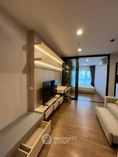 Modern apartment with open living room and bedroom, featuring sleek furniture and ambient lighting.