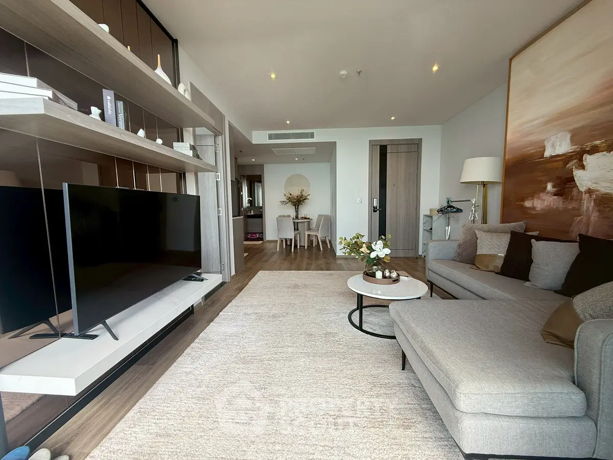 Spacious modern living room with elegant decor and large TV, perfect for relaxation and entertainment.