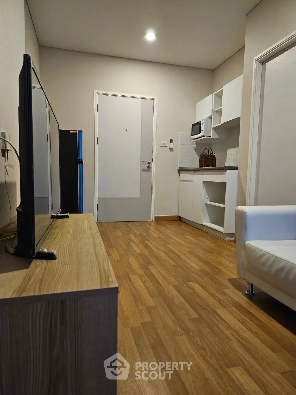 Modern living room with wooden flooring and compact kitchen area