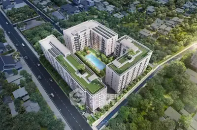 Stunning aerial view of modern residential complex with lush green rooftops and central pool, surrounded by greenery.
