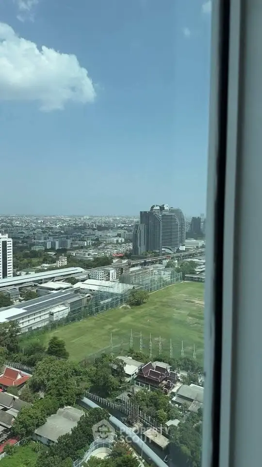 Stunning cityscape view from high-rise building window showcasing urban skyline and green spaces.