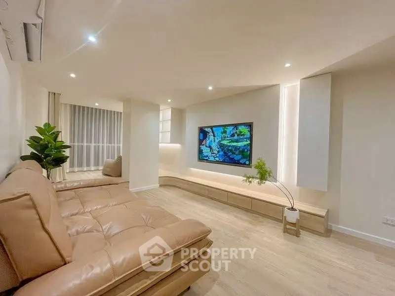 Modern living room with sleek design, featuring a large TV and comfortable seating.