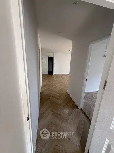 Spacious hallway with elegant herringbone wood flooring in modern apartment