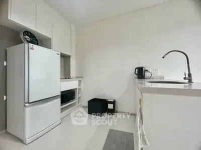 Modern kitchen with sleek white cabinets and appliances, featuring a spacious fridge and stylish sink area.