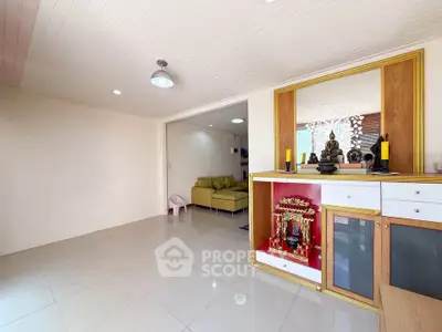 Spacious living room with modern decor and ample natural light, featuring a cozy seating area and elegant display cabinet.