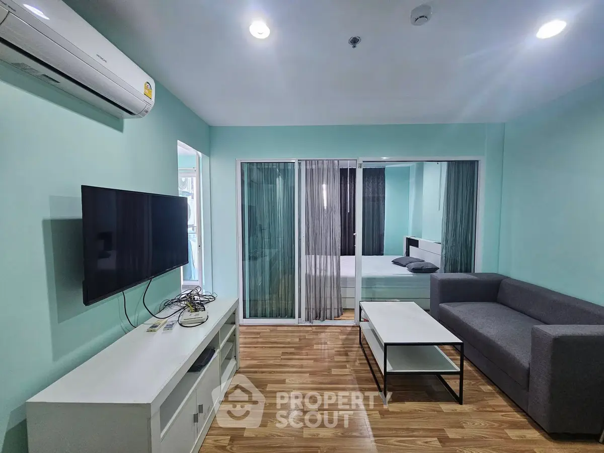 Modern living room with sleek design, featuring a large TV, comfortable sofa, and stylish wooden flooring.