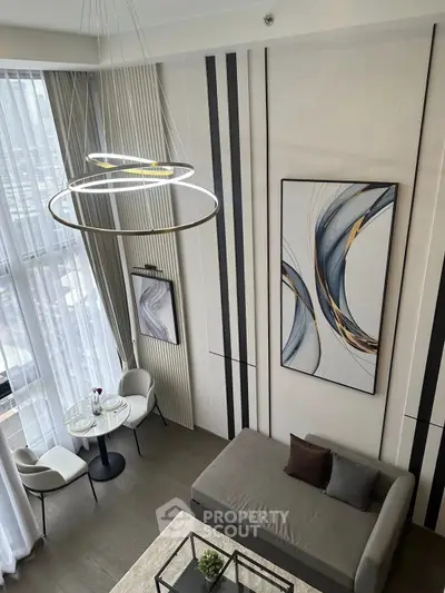 Modern living room with high ceilings, elegant chandelier, and stylish decor in a luxury apartment.