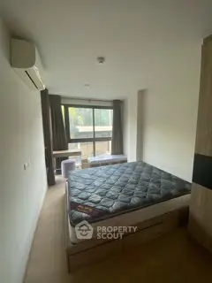 Spacious bedroom with large window and modern furnishings in a stylish apartment.