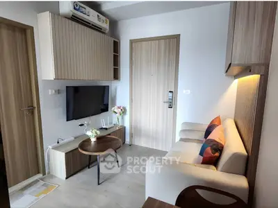 Modern living room with sleek furniture and wall-mounted TV in a cozy apartment.