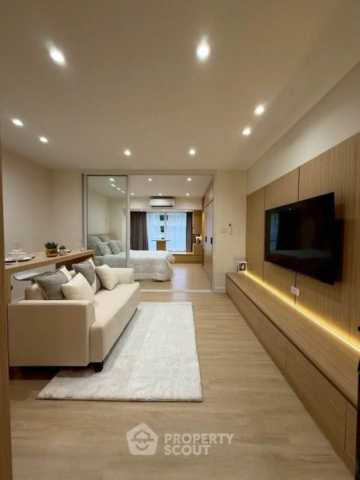 Modern living room with cozy sofa, stylish lighting, and sleek TV setup in open-concept apartment.