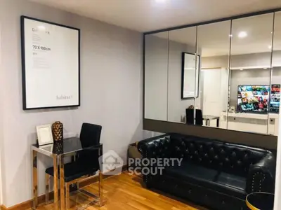 Stylish living room with black leather sofa and mirrored wall, perfect for modern urban living.