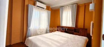 Cozy bedroom with wooden walls and natural light, featuring a comfortable bed and elegant curtains.