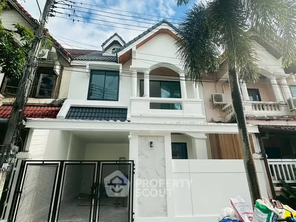 Charming two-story townhouse with modern facade and gated entrance in a serene neighborhood.