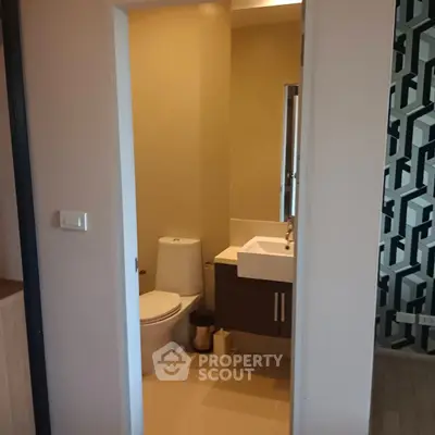 Compact bathroom with modern fixtures and geometric wall design