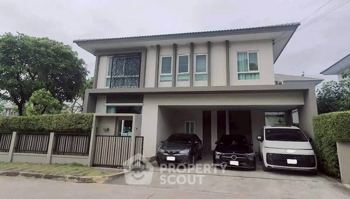 Modern two-story house with spacious driveway and parked cars in a serene neighborhood.