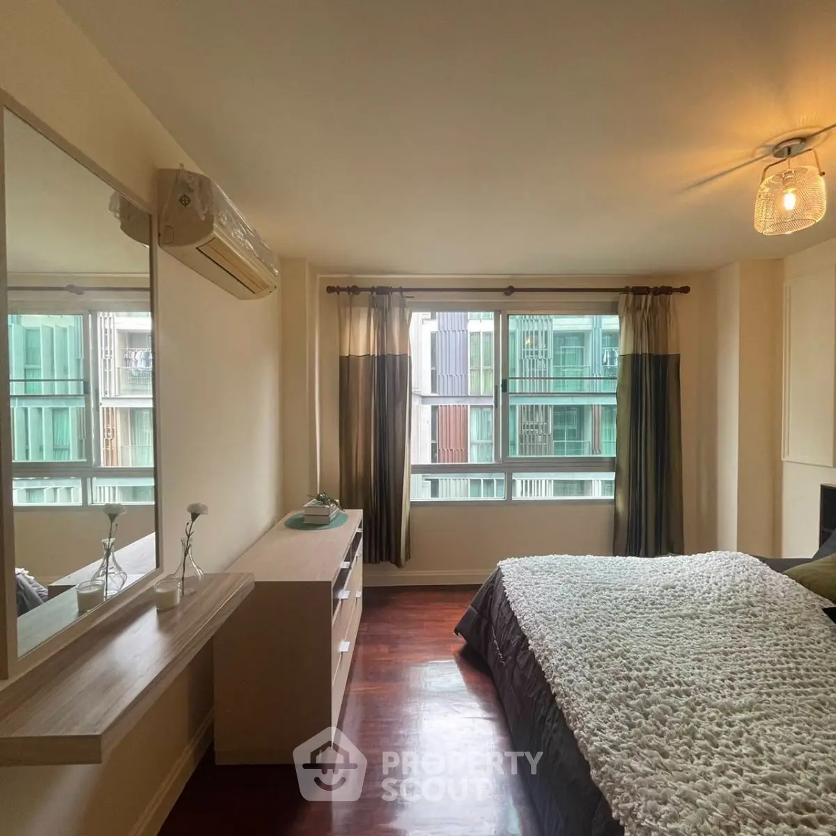 Spacious bedroom with large windows and modern decor in a high-rise apartment.
