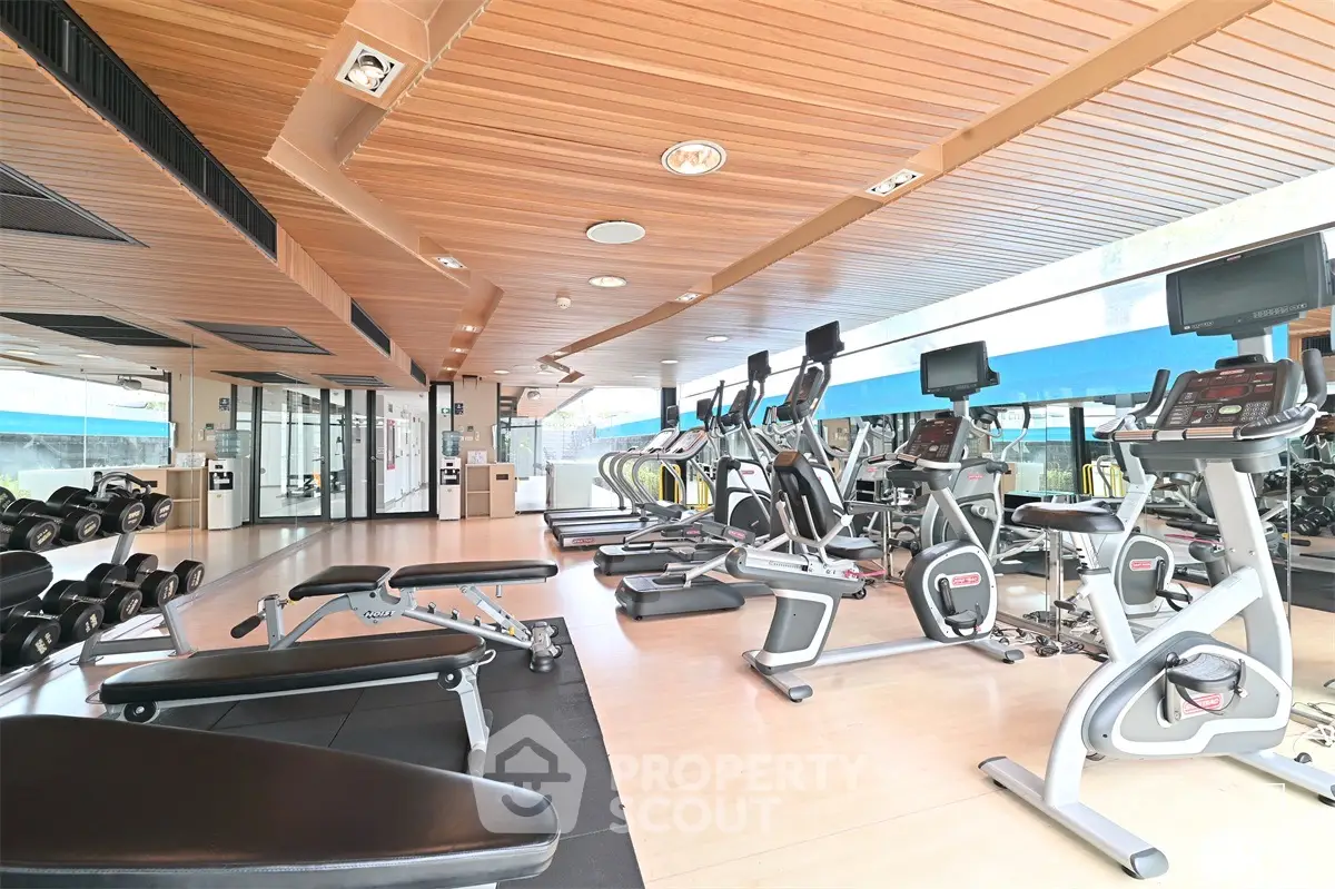 Modern gym with state-of-the-art equipment and wooden ceiling in luxury residential building.